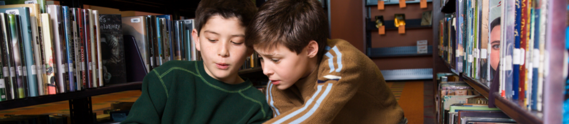 2 boys talking between bookshelves